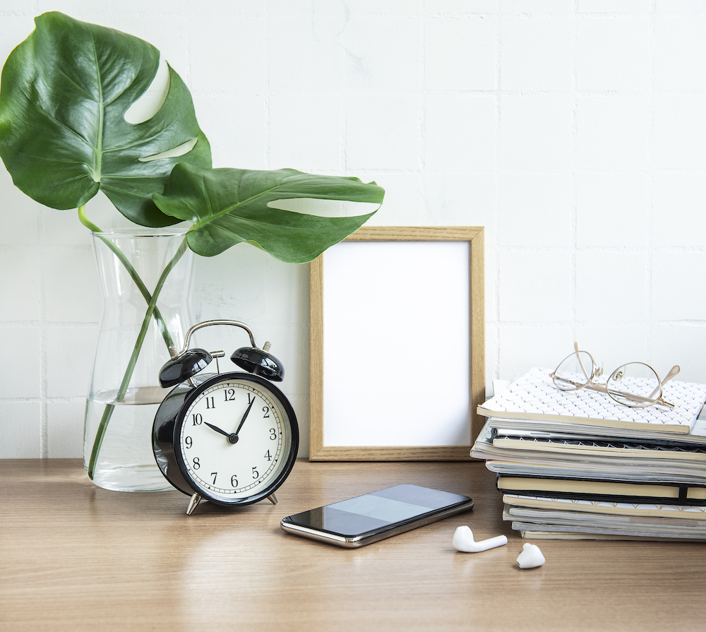 Office desk with stack of notepads Office desk with stack of notepads, alarm clock, office supplies and house plants